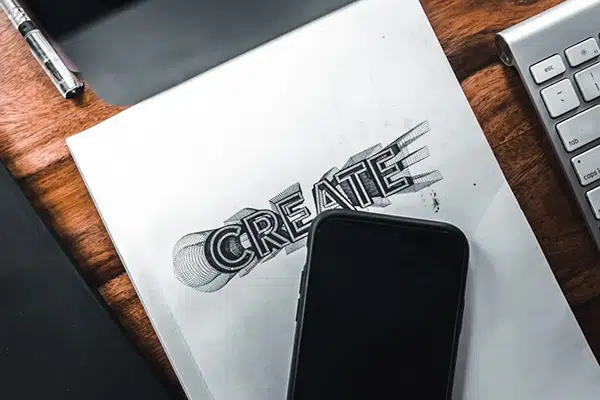 Phone and paper on a desk that says "Create"