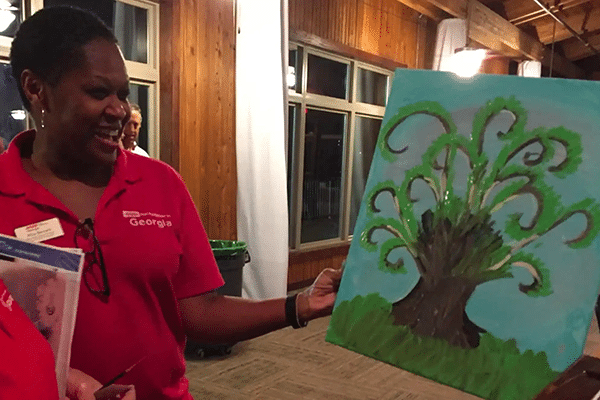 Woman shows her painting at a Foundation for Art & Healing event